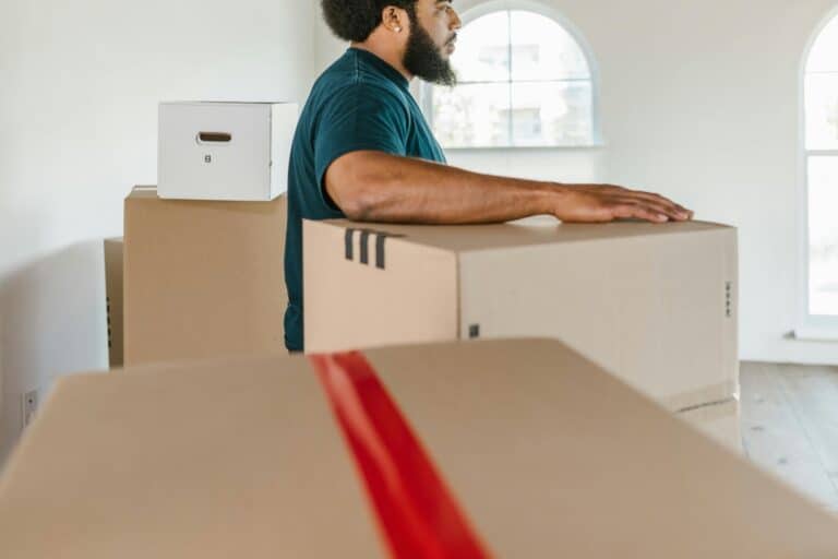 Side view of a professional mover surrounded by boxes, in the concept of a Good Man and Van in Greenwich