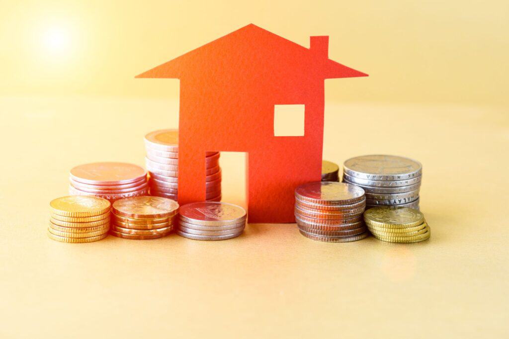 A paper house surrounded by coins in the concept of saving money when moving to Greenwich.