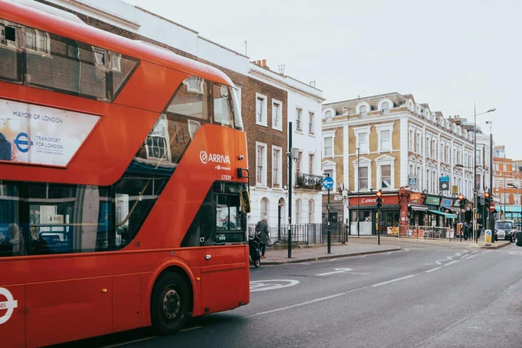 The red bus on a street with few vehicles