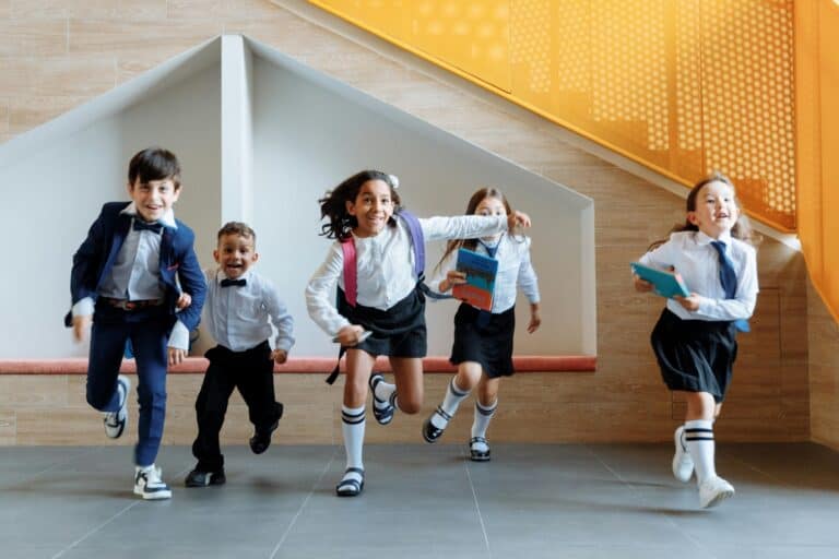 A group of young children wearing uniform and gleefully running in the concept of schools in Greenwich.