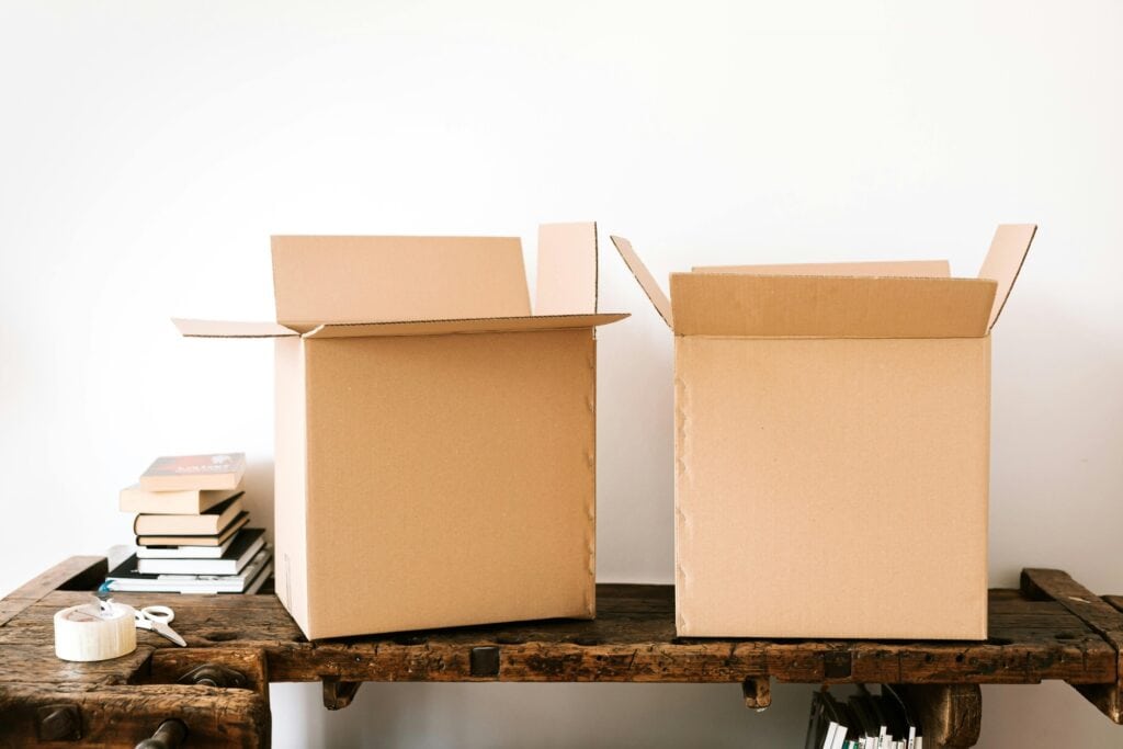 Empty cartons, pair of scissors, and packing tape on the table